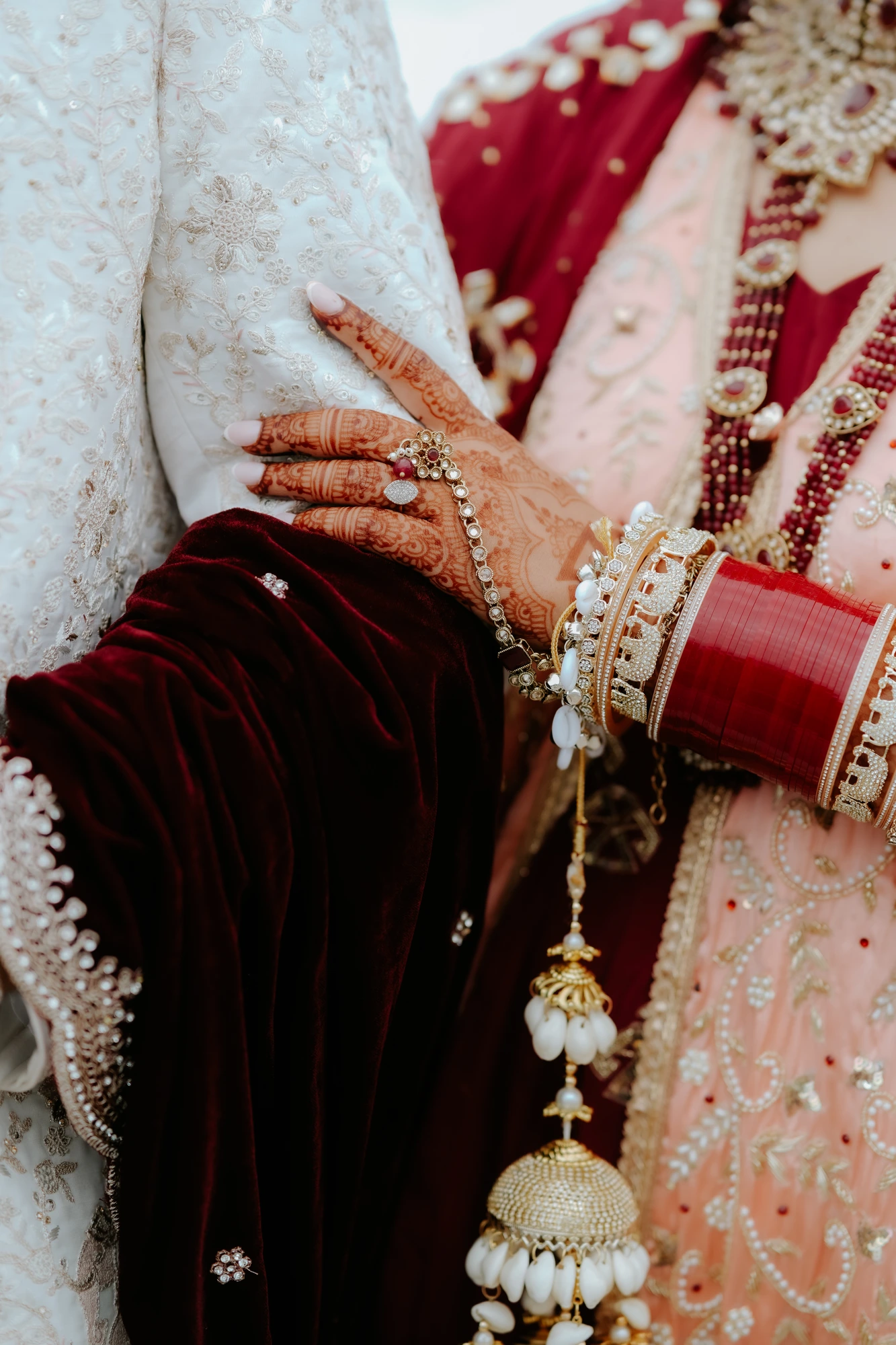Henna-adorned hand with bridal bangles and kalire